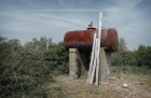 13: Rusting tank with poles